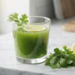 Fresh glass of coriander-lemon water remedy with floating lemon slice and coriander leaves on a marble counter, illustrating a natural drink for managing high uric acid.